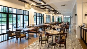 A spacious restaurant with high ceilings, large windows, and a patterned floor. Tables and chairs are arranged for dining. - Chaanburi Boutique Resort (Chanthaburi)