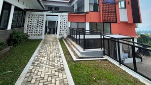 A modern hotel with a brick pathway leading to the entrance, a covered outdoor area, and a clear sky. - Aldeoz Ciater (Ciater)