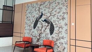 A modern interior with two red chairs, a table, and a wall with a peacock mural. - Aldeoz Ciater (Ciater)