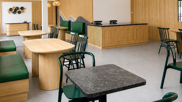 A modern cafe with wooden furniture and green chairs, a counter with a menu, and pendant lighting. - Aldeoz Ciater (Ciater)