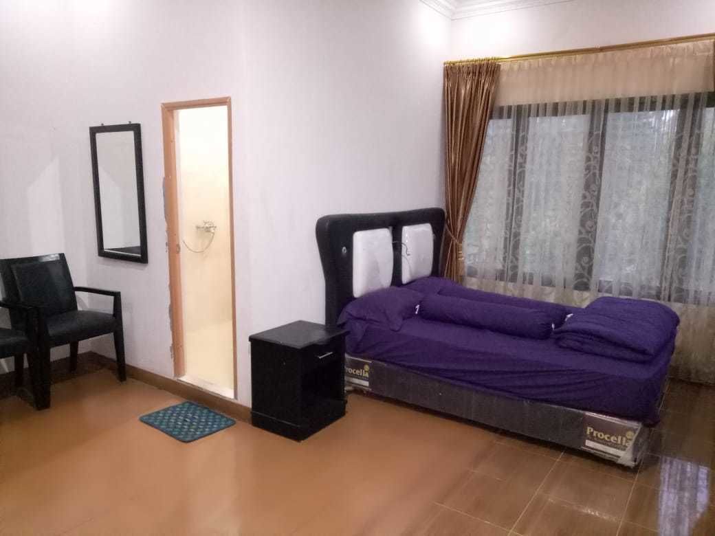 A bedroom with a bed, a chair, a small table, and a window with curtains.