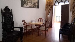 A dining area with a round table and chairs, a large framed artwork on the wall, and a door leading to another room. - Aldeoz Dempo Pagar Alam Villa Sumsel (Pagar Alam)