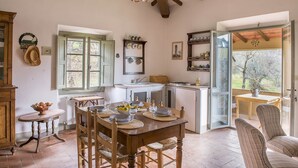Una cucina accogliente con mobili in legno, un tavolo da pranzo per quattro persone e vista all'esterno tramite una porta vetrata.