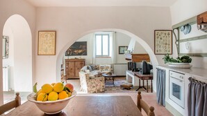 Una cucina accogliente con un tavolo di legno, una ciotola di frutta e un divano sullo sfondo.