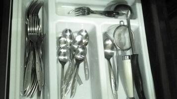 A drawer containing a set of silverware including forks, spoons, and a knife.