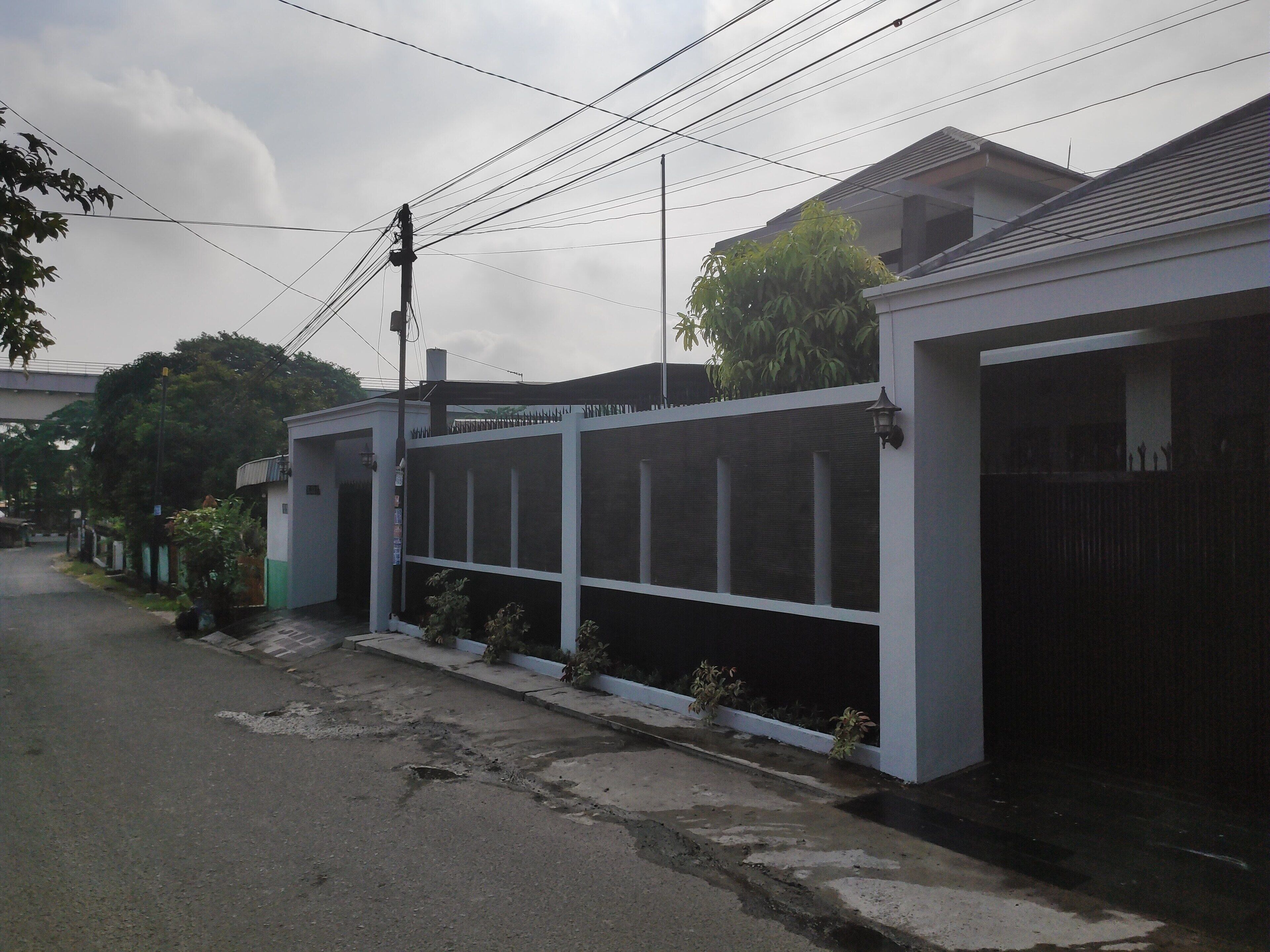 A residential street with houses, a fence, and utility poles.