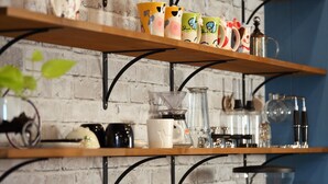 A kitchen area with shelves holding various kitchenware and appliances.
