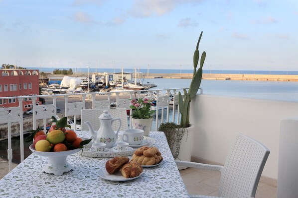 A balcony with a table set for breakfast, overlooking a marina with boats and a calm sea. - CHARMING REAL HOUSE SEA VIEW INDEPENDENT TERRACES (Monopoli)