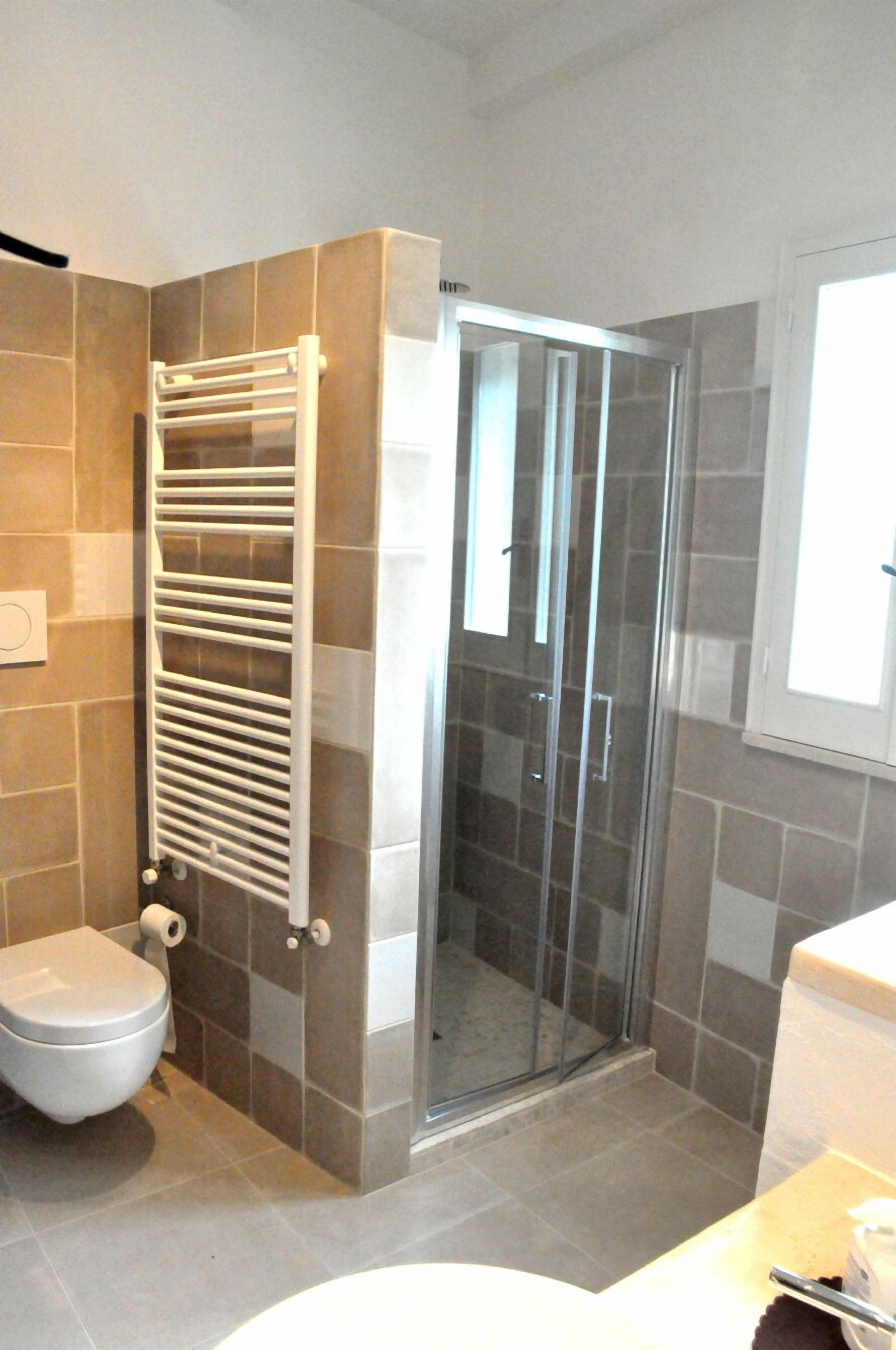Een badkamer met een douchecabine van glas, een wit toilet en een handdoekhouder.