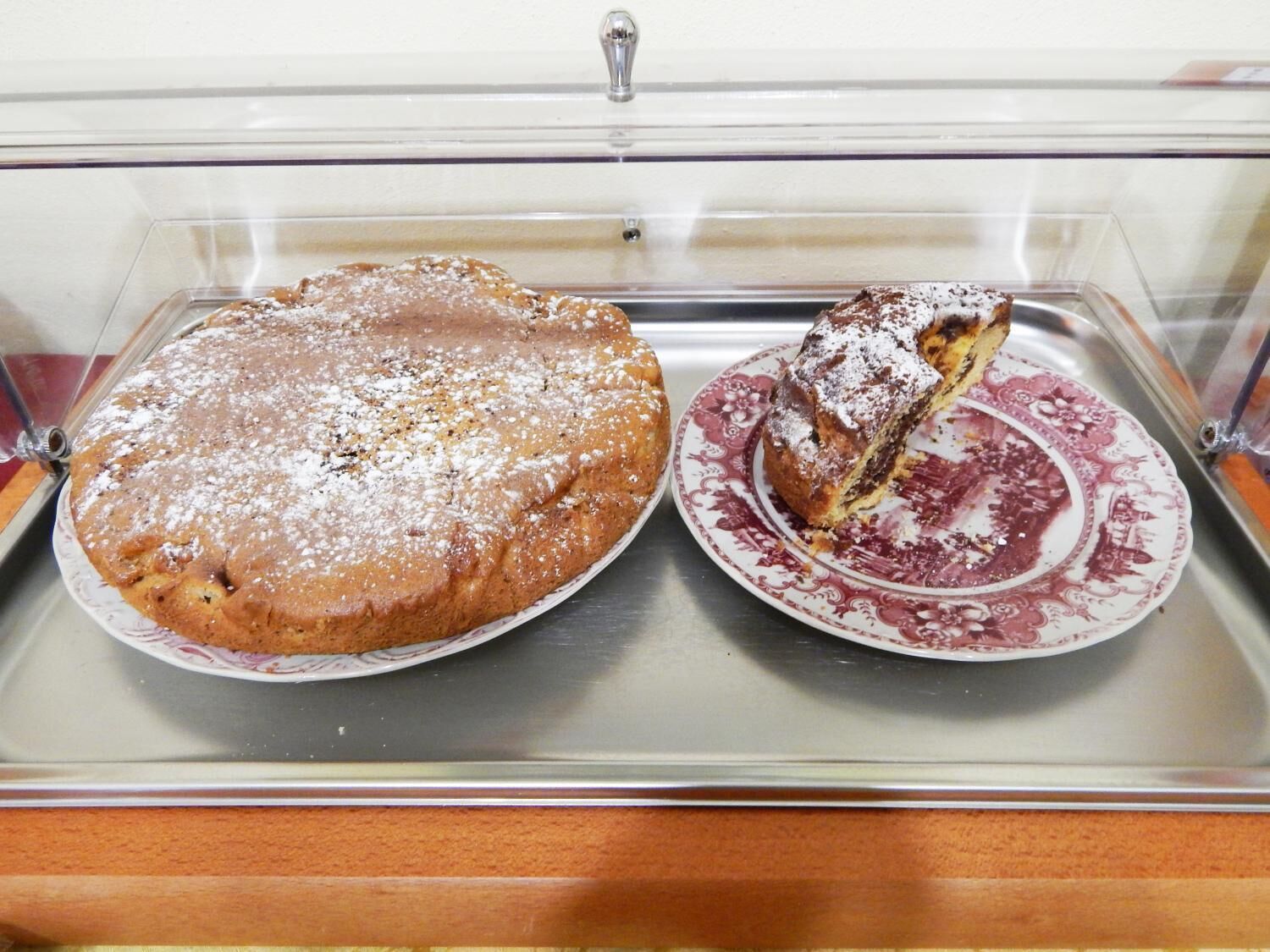 A dessert display case with a round cake and a slice on a plate.