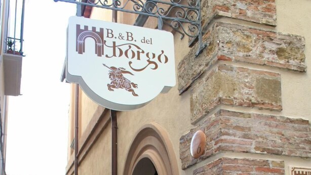 Een smalle straat met een gebouw en een bordje voor 'B&B del Borgo'.