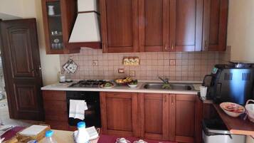 Cucina con mobili in legno, piano cottura a gas, lavello e macchina da caffè.