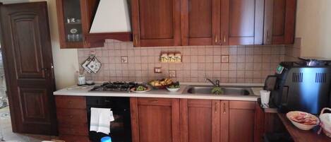 Una cocina con armarios de madera, estufa a gas, un lavabo y una cafetera.