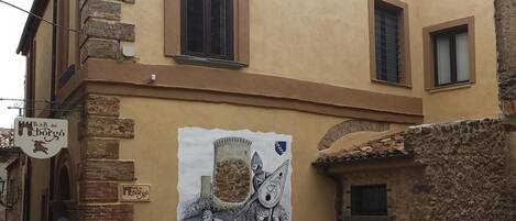 A building with a mural of a medieval scene, stone walls, and a sign for B&B del Borgo.