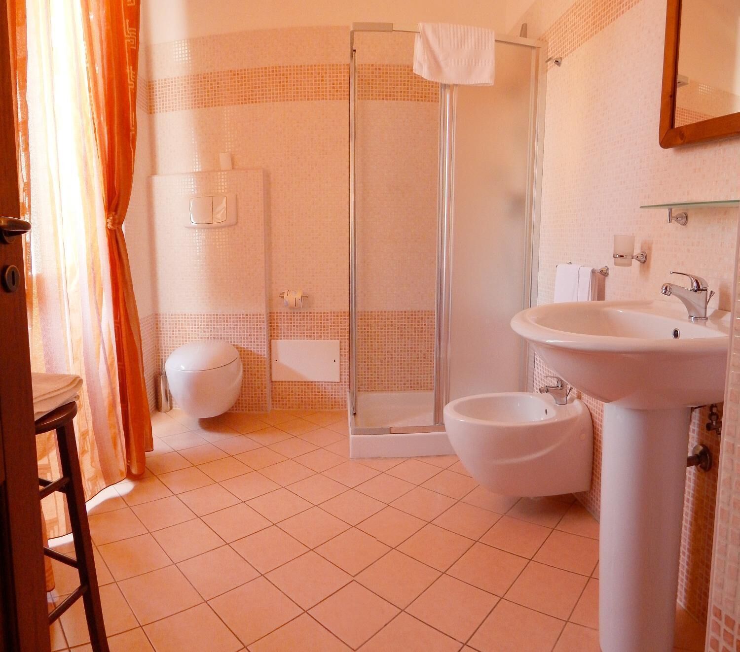 A bathroom with a shower, toilet, bidet, and sink.