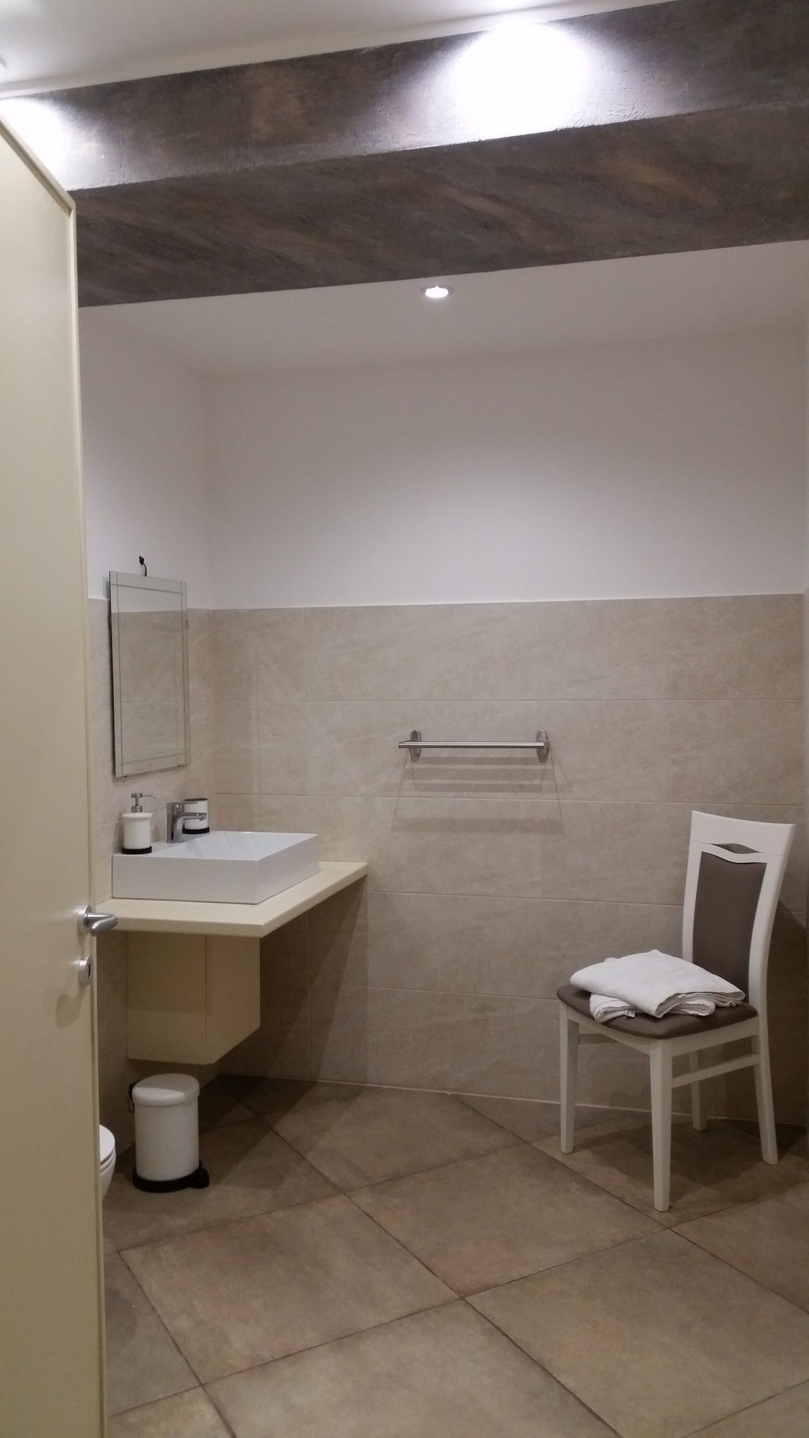 Un baño con lavamanos blanco, espejo y perchero.