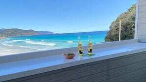 Un balcón con vistas al océano, dos botellas de Corona y un cuenco de fruta.