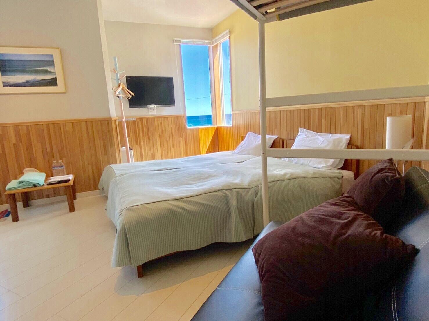 A room with a bunk bed, a bedside table with a lamp, a TV, and a window with a view.