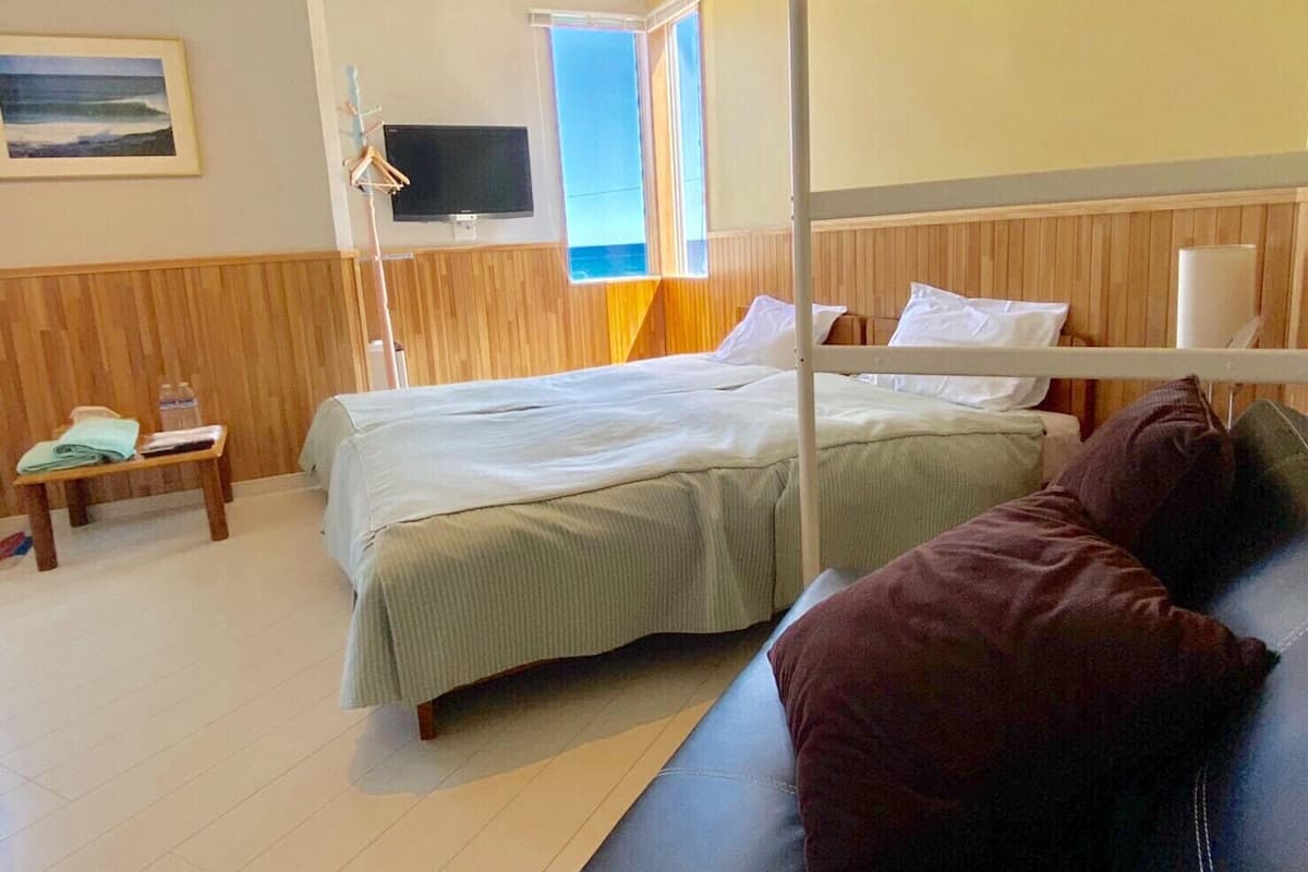 A room with a bunk bed, a bedside table with a lamp, a TV, and a window with a view.