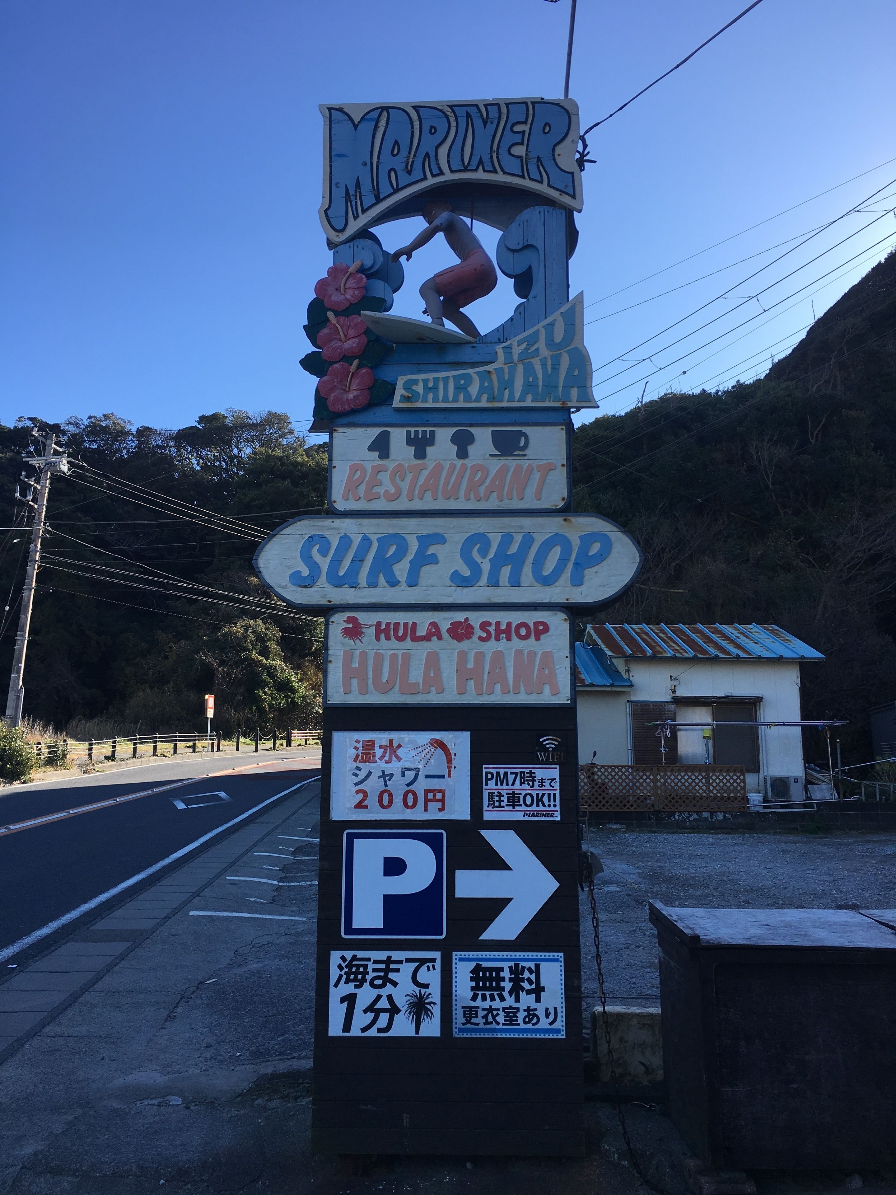 A signpost with multiple directions and names, including 'Mariner', 'Shirahama', 'Restaurant', 'Surf Shop', and 'Hula Shop Hula Hana'.