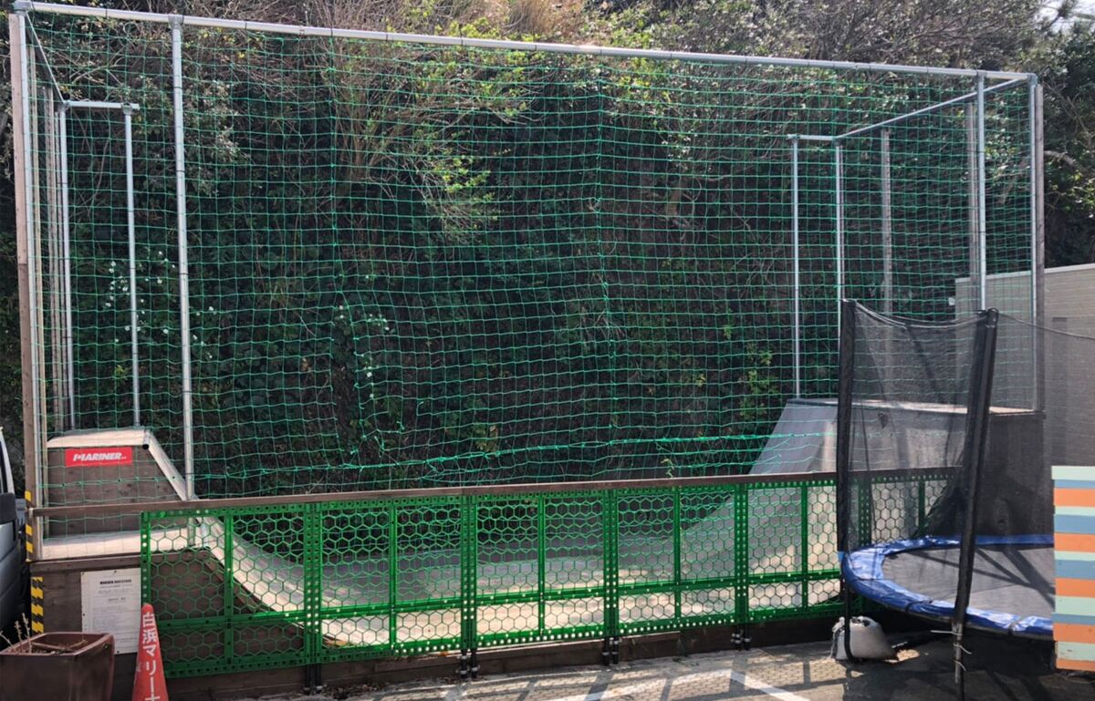 Un área cercada con un trampolín y un recinto cubierto de red.