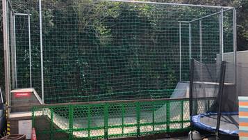 Un área cercada con un trampolín y un recinto cubierto de red.