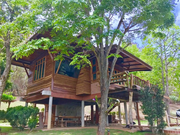 Una cabaña de madera con balcón, rodeada de árboles y follaje.