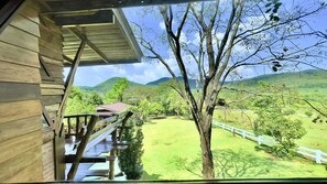 Una cabaña de madera con un porche que da a un paisaje verde y colinas.