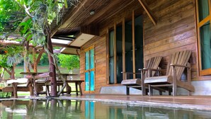 Una cabaña de madera con piscina, sillas de madera y una mesa.