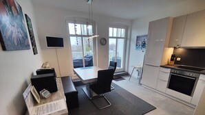 A modern kitchen with a built-in oven, a dining area with a bench, and a large window providing natural light. - 3-room vacation apartment Villa Parkblick, 55 inch UHD, Blu-ray, renovated in 2024 (Kühlungsborn Ost)