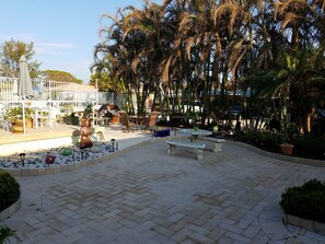 An outdoor patio area with seating, a decorative Buddha statue, and a variety of potted plants. - Beach studio with pool 200 meters from the beach (Boynton Beach)