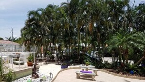 An outdoor patio area with seating, palm trees, and potted plants. - Beach studio with pool 200 meters from the beach  (Boynton Beach)