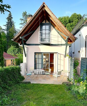 A two-story house with a sloped roof, large windows, and a patio with outdoor furniture.