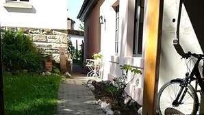 Un chemin menant à une maison avec un mur en pierre et un vélo garé à l’extérieur.