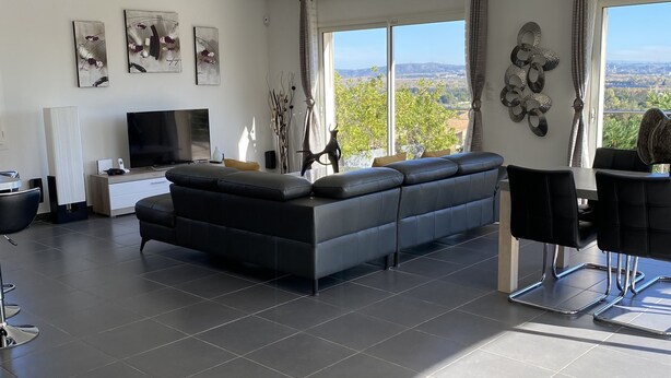 Una sala moderna con un sofá seccional grande, un televisor de pantalla plana y un comedor con mesa y sillas.