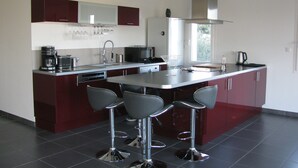 Una cocina moderna con una isla central, taburetes de bar, una cafetera y un microondas.