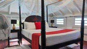 Een hemelbed met een baldakijn, twee nachtkastjes met lampen, en uitzicht op de omgeving door een raam.