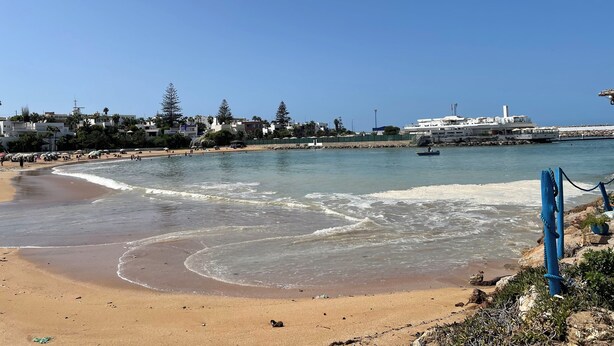 A beach with a rocky shoreline, waves, and a clear sky. - At the heart of Rabat Beaches (Harhoura)