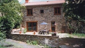 A stone house with a tiled roof, a small porch with a table and chairs, and a stone wall surrounding the property. - 4* located in small village in Auvergne in the middle of the country (Saint-Étienne-Sur-Blesle)