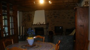 A dining area with a round table, chairs, a vase with flowers, a fireplace, and a stone wall. - 4* located in small village in Auvergne in the middle of the country (Saint-Étienne-Sur-Blesle)