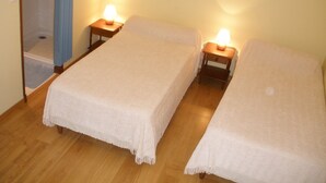 A small, cozy room with two single beds, each with a bedside table and a lamp. - 4* located in small village in Auvergne in the middle of the country (Saint-Étienne-Sur-Blesle)