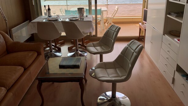 A room with a dining table set for two, a sofa, and a view of the sea. - Caravelles palace ***** the most beautiful apartment in Arcachon on the beach (Arcachon)
