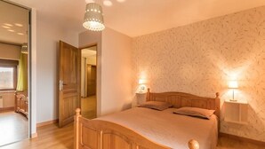 A bedroom with a wooden bed, two bedside lamps, and a patterned wallpaper. - Gîte du Champ Chequelin - 3 ears 4 stars (Corravillers)
