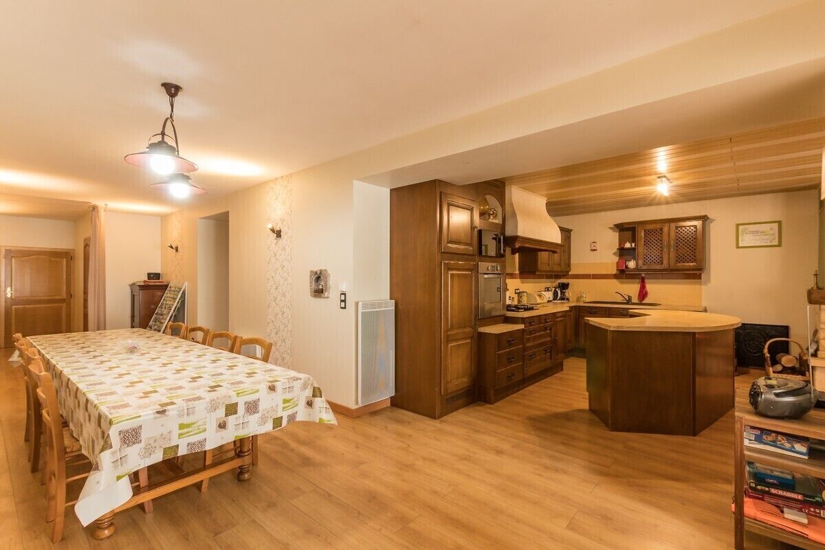 A kitchen with wooden cabinets, a central island, and a dining table with a tablecloth.