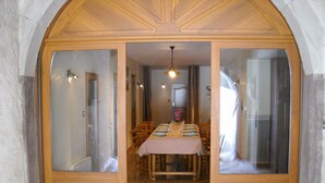 A dining area with a table set for four, wooden doors with glass panels, and a ceiling light fixture. - Gîte du Champ Chequelin - 3 ears 4 stars (Corravillers)