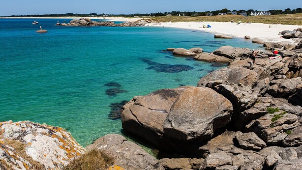 A rocky shoreline with clear turquoise water, a sandy beach, and a few people in the distance. - Quiet, 3-star rated house, 800m from beaches and coastal paths (Tregunc)