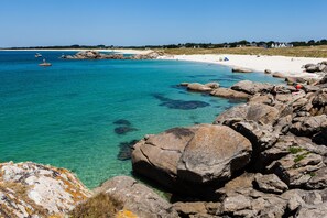 Eine Küstenlandschaft mit klarem türkisblauem Wasser, Felsenformationen und einem Sandstrand.