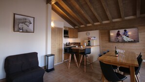 Un'accogliente cucina con travi in legno, una zona pranzo con tavolo e sedie, e un soggiorno con divano.