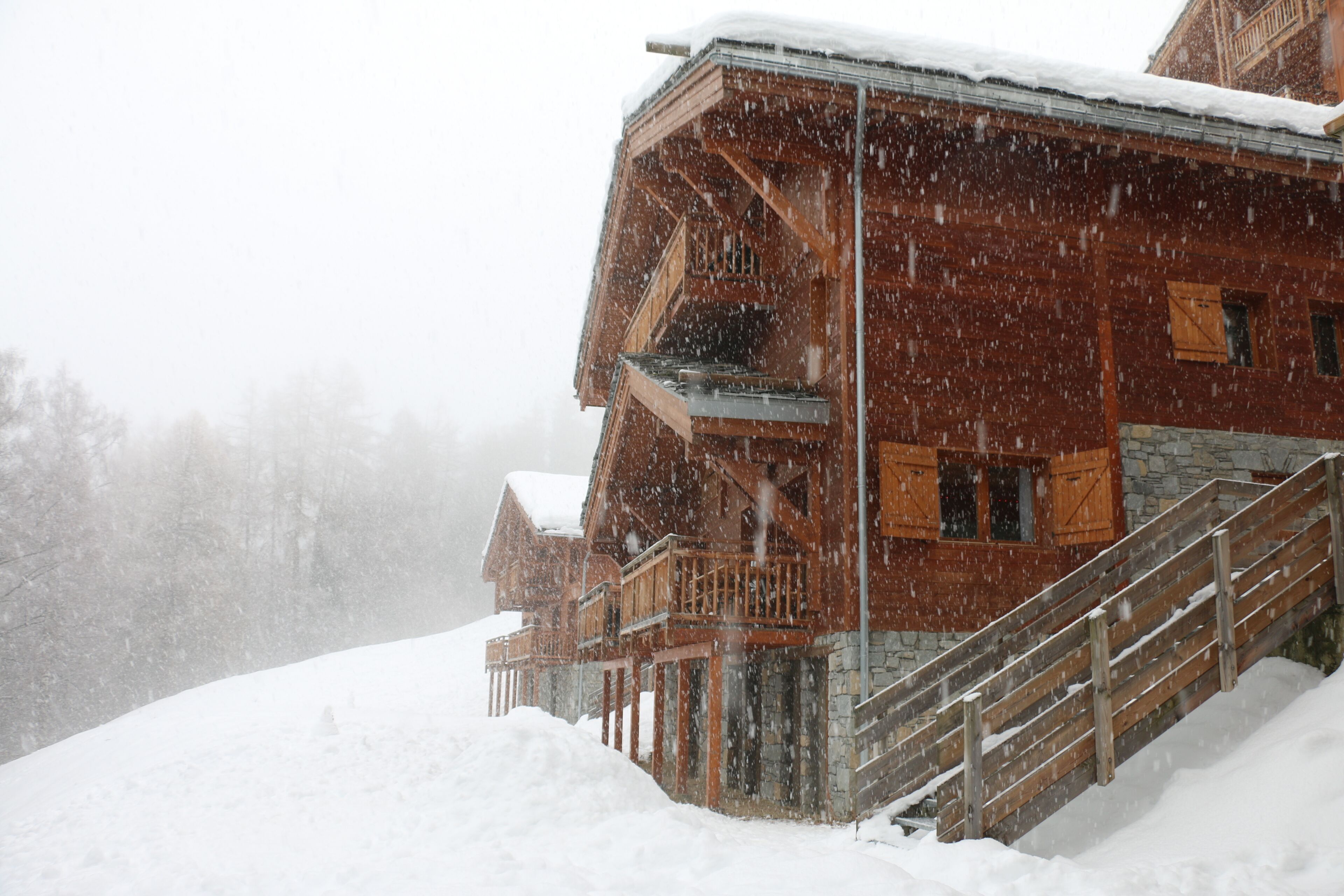 Un edificio de madera con balcón y escaleras, rodeado de nieve.