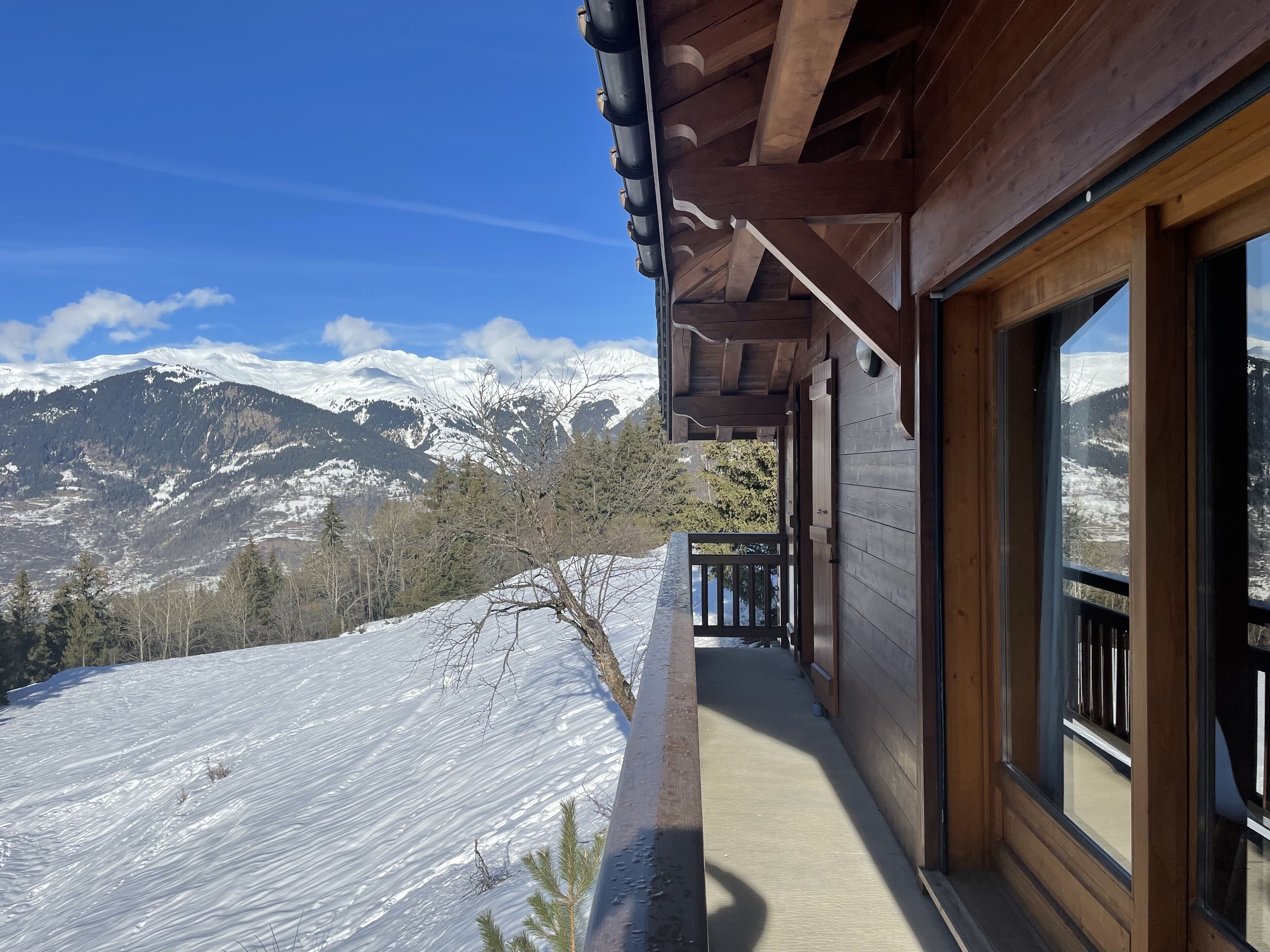 A wooden building with a balcony overlooking a snowy mountain landscape.